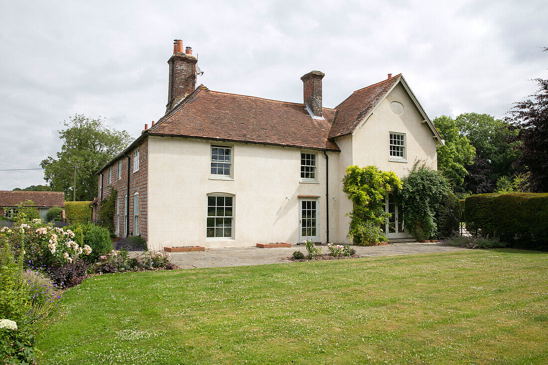 Gepflasterte Terrasse und Rasen eines freistehenden Hauses in Hampshire, England UK