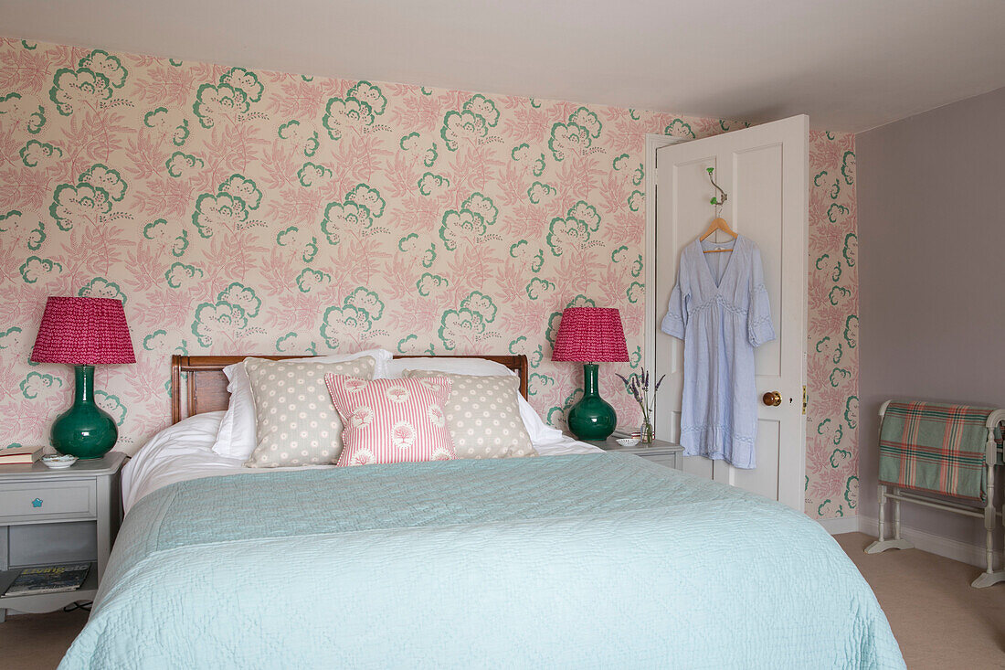 Pair of lamps with patterned wallpaper and turquoise bed cover in Hampshire home England UK