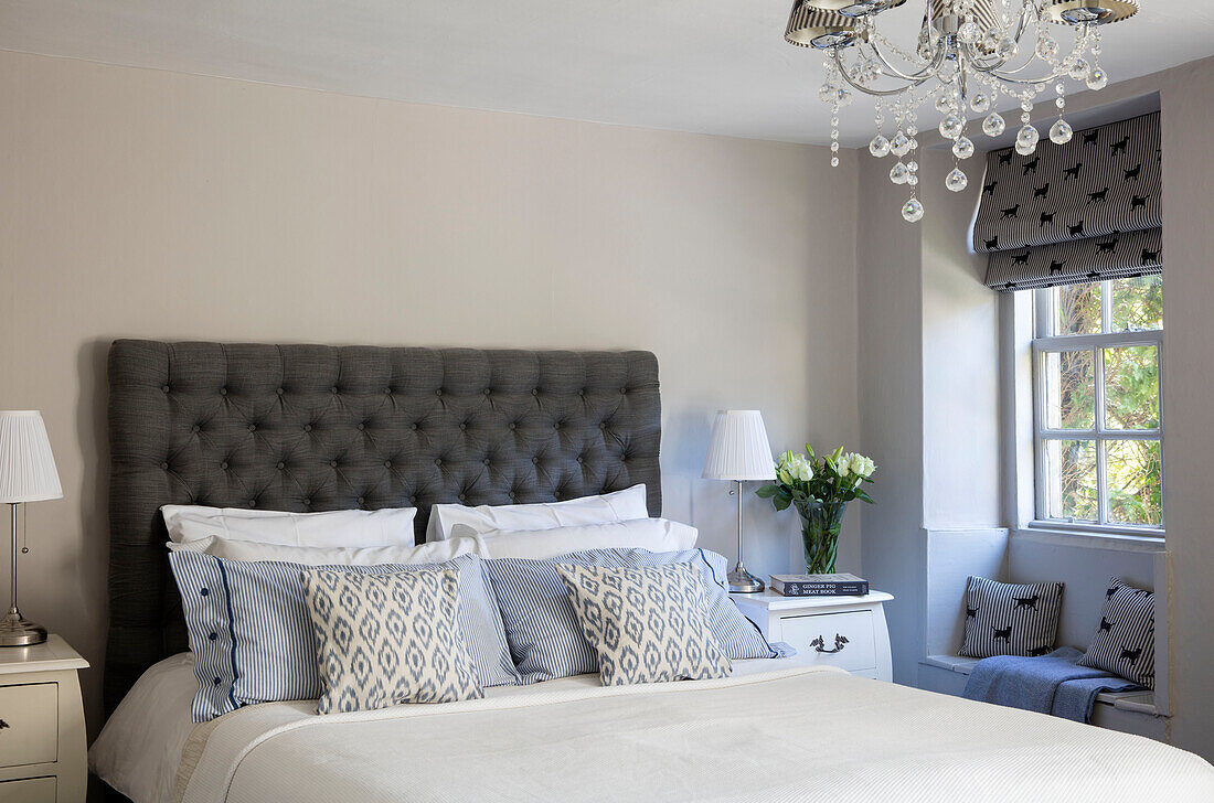 Graues und weißes Schlafzimmer mit geknöpftem Kopfteil und Nachttischlampen in einem Cottage in Wiltshire UK