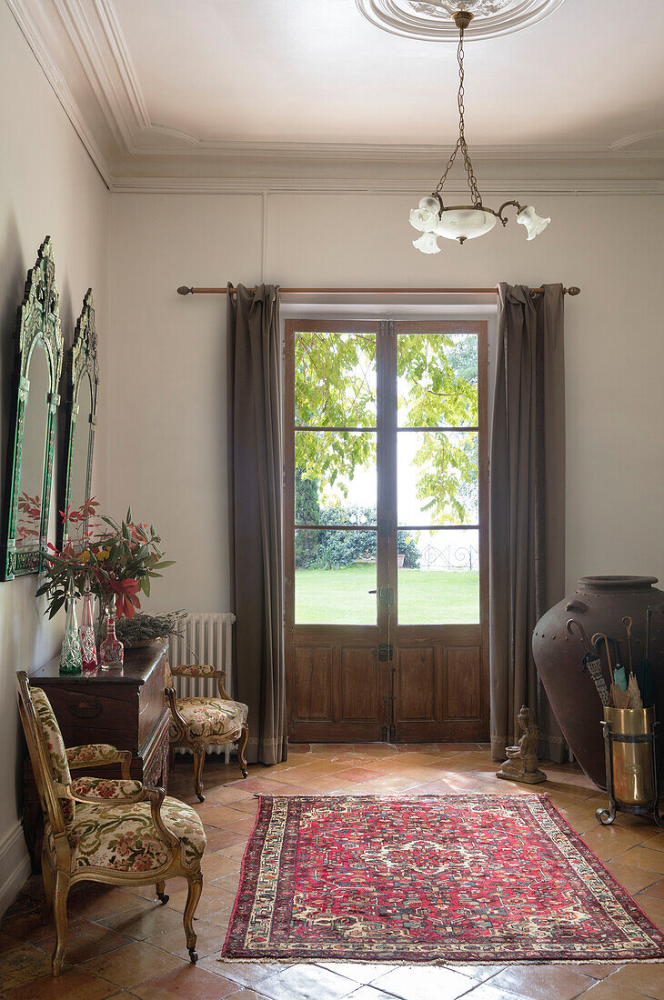 Venetian mirrors with tapestry chairs and French doors in French chateau Lot et Garonne