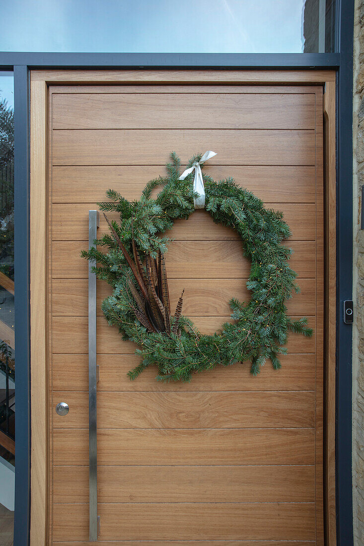 Christmas wreath with pheasant feathers on front door of 1960s country house West Sussex UK