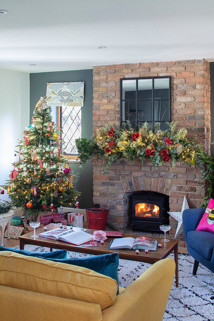 Freigelegter Ziegelsteinkamin und Weihnachtsbaum im Wohnzimmer eines Hauses in Surrey UK