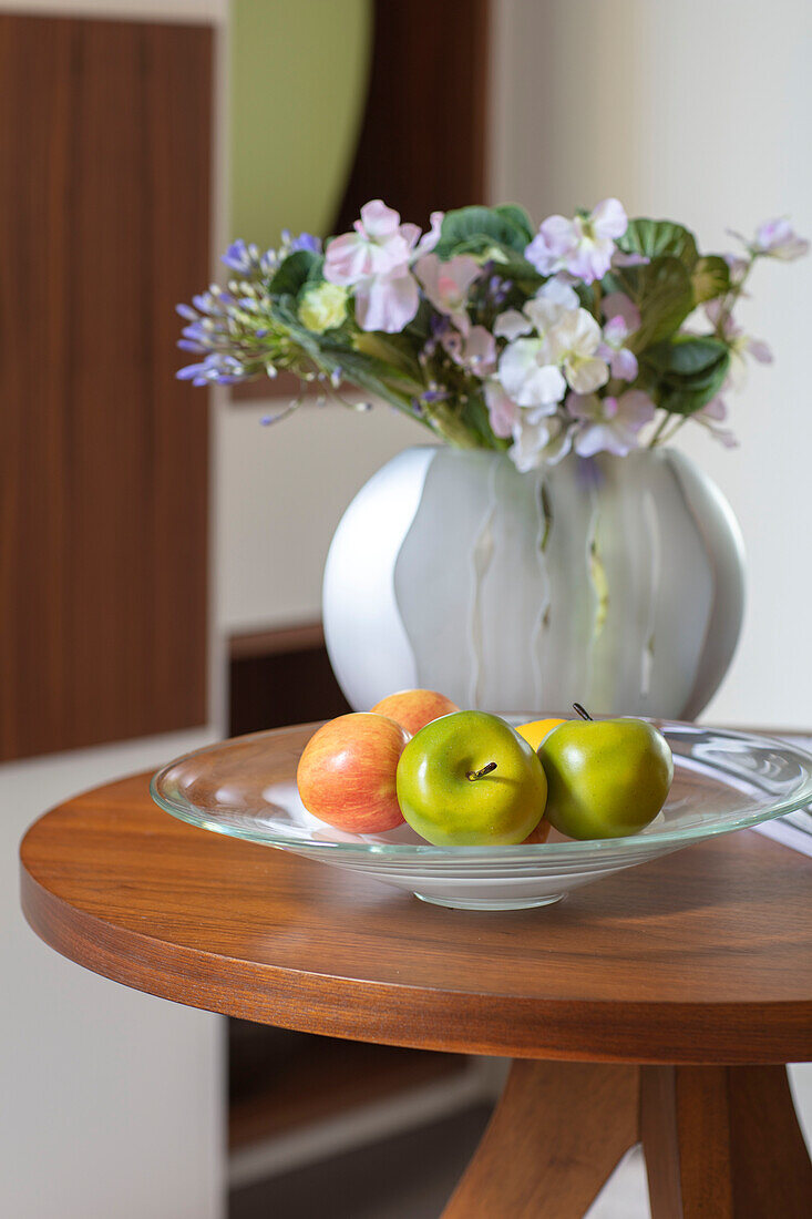 Vase mit Blumen und Schale mit Äpfeln auf einem Tisch London UK