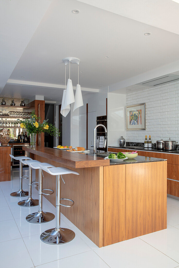 Verchromte Barhocker an einer Holzinsel in einer Küchenerweiterung in einem Londoner Haus UK