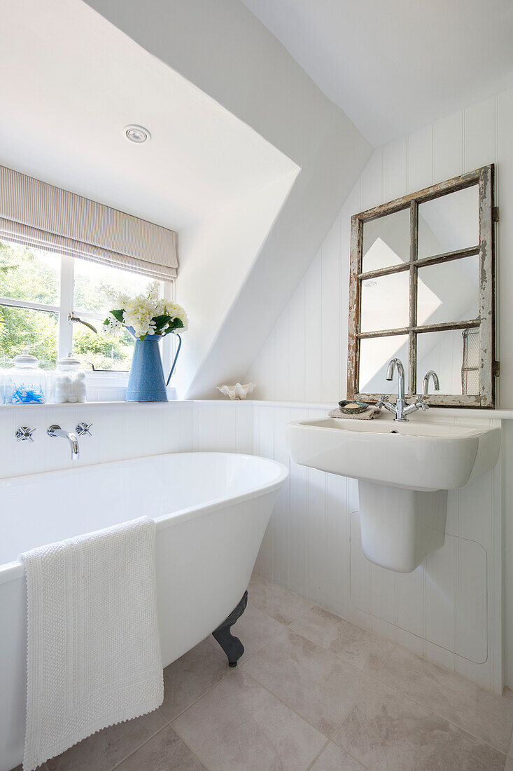 Kleine freistehende Badewanne an einer Dachgaube in einem Landhaus in Surrey, Großbritannien