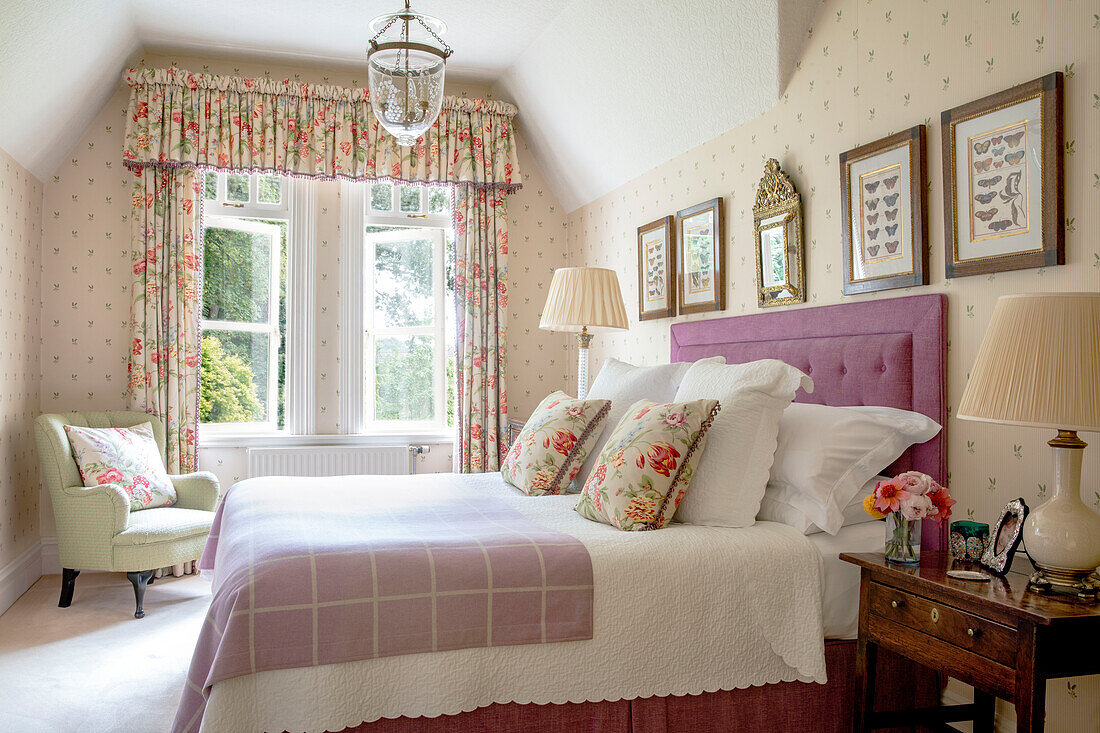 Geblümte Vorhänge in einem sonnenbeschienenen Schlafzimmer mit gerahmten Schmetterlingsdrucken Wales UK