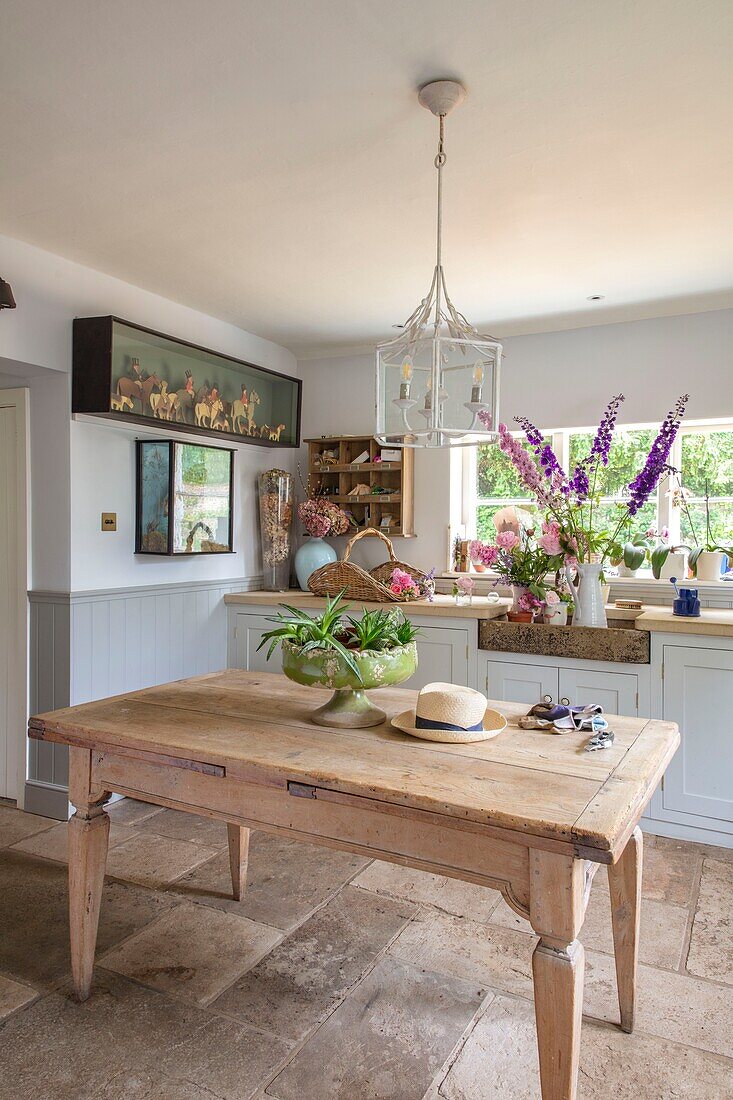 Rustic pine table in white and pale blue kitchen in elegant Hampshire home UK