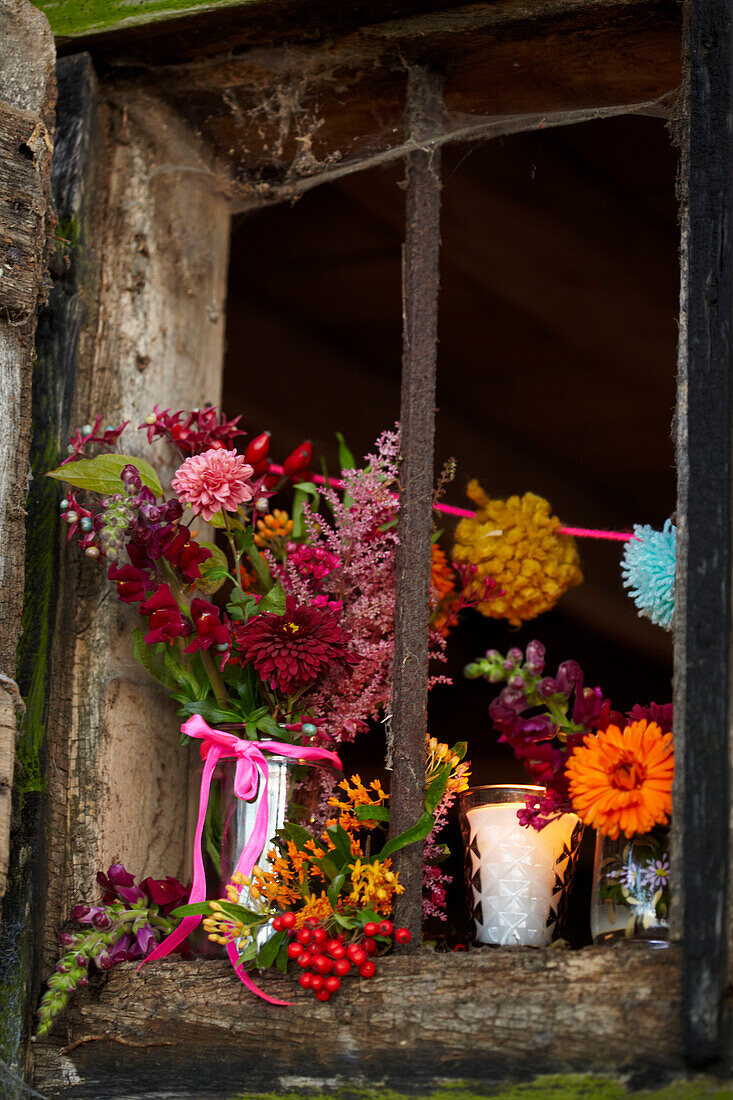Cut flowers in window of rustic wood cabin in Autumn UK