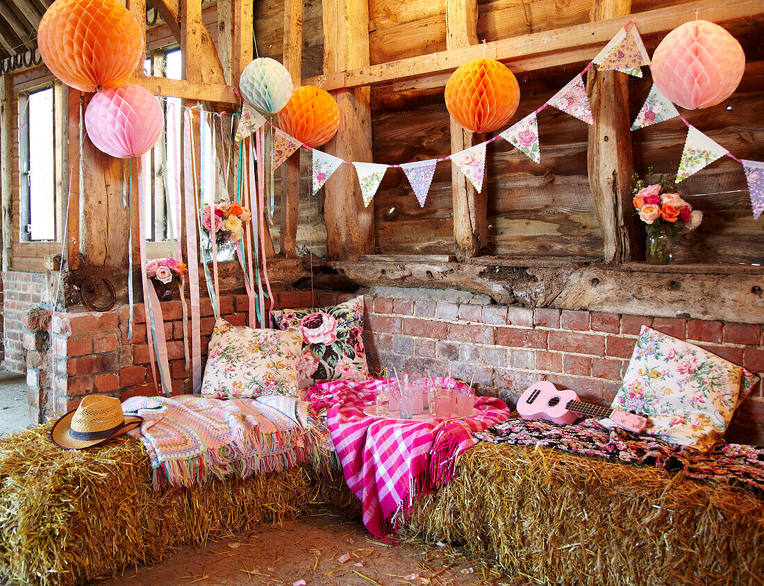 Ukulele and floral cushions on haybale seating with bunting in late summer