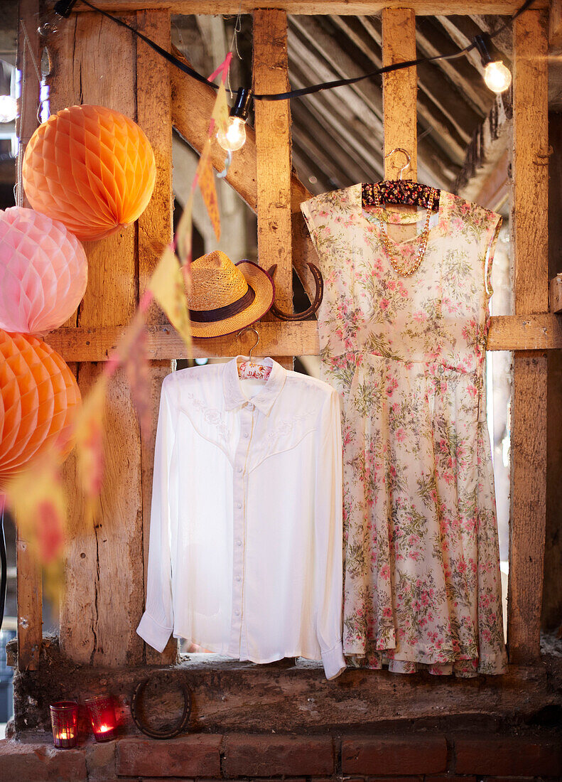 Kleid und Hemd hängen mit Papierkugeln in einer Fachwerkscheune im Spätsommer