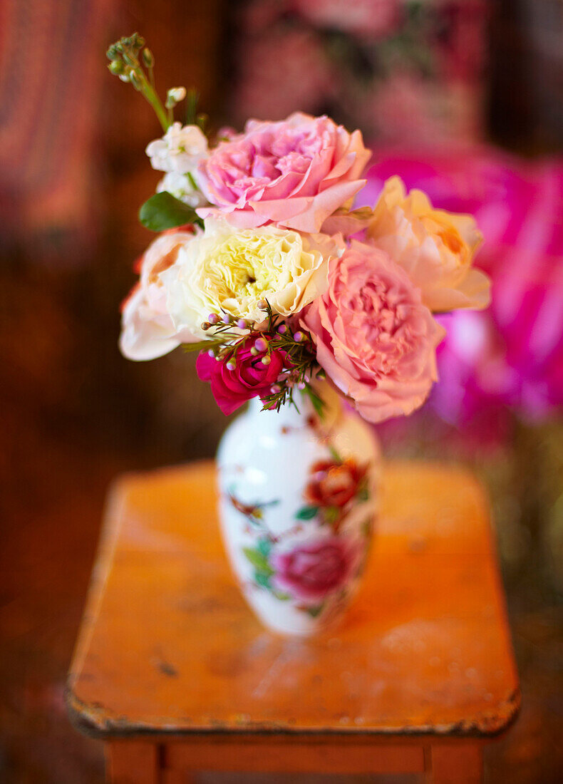 Vase mit Schnittblumen auf orangefarbenem Beistelltisch