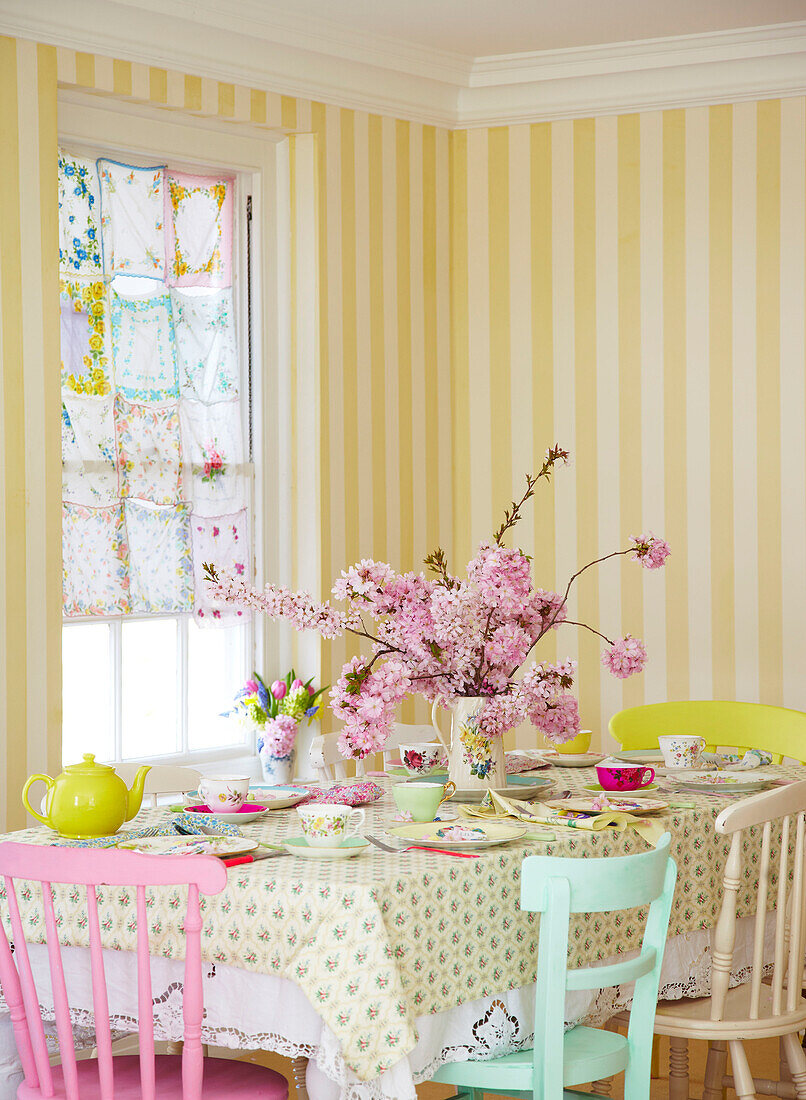 Rosa Blüte auf Tisch in Zimmer mit gelber Streifentapete