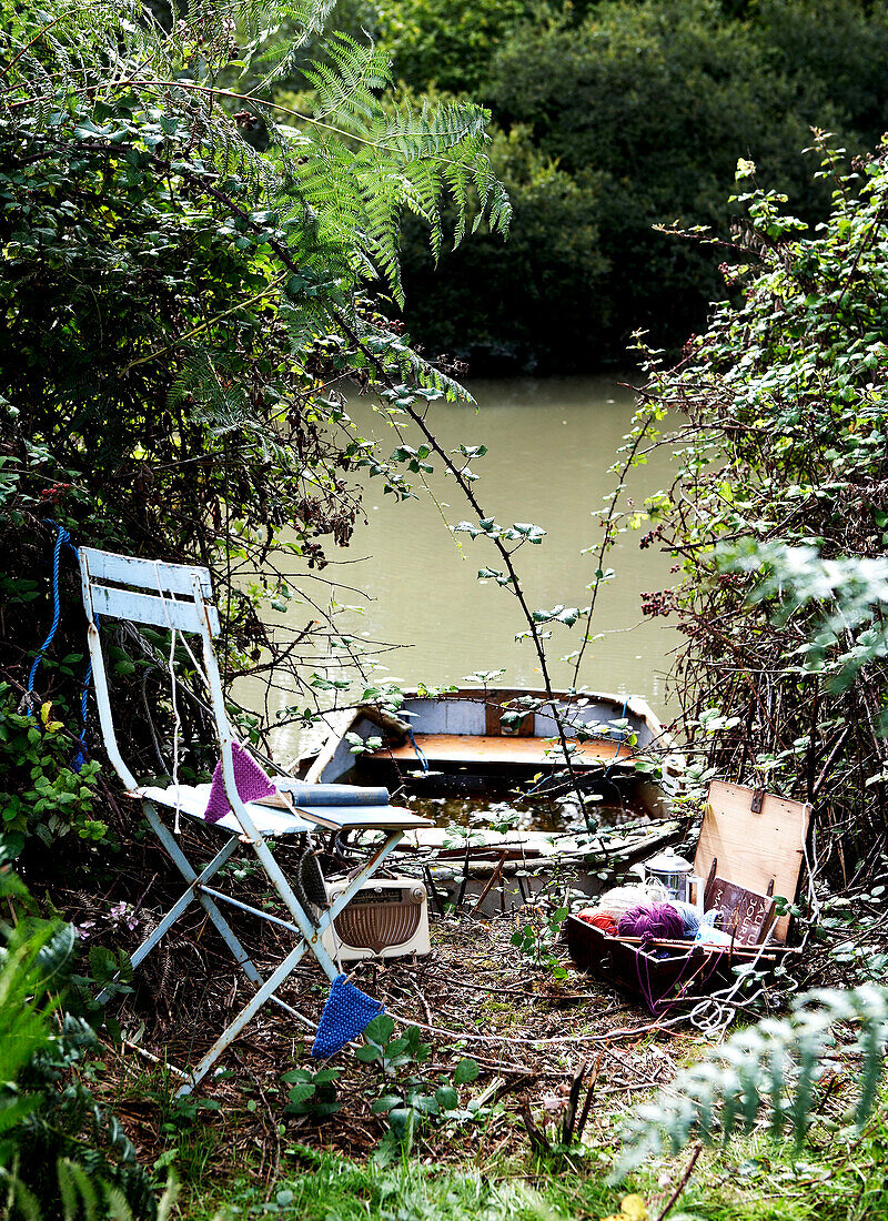 Rowing boat moored on riverbank with folding chair bunting and wool Isle of Wight, UK
