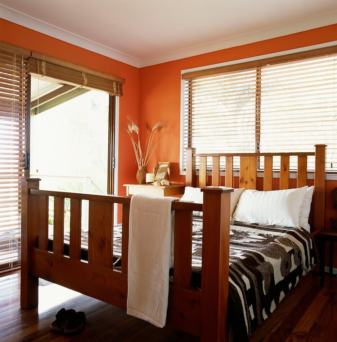 Orange gestrichenes Schlafzimmer mit Terrassenschiebetüren und einem Doppelbett
