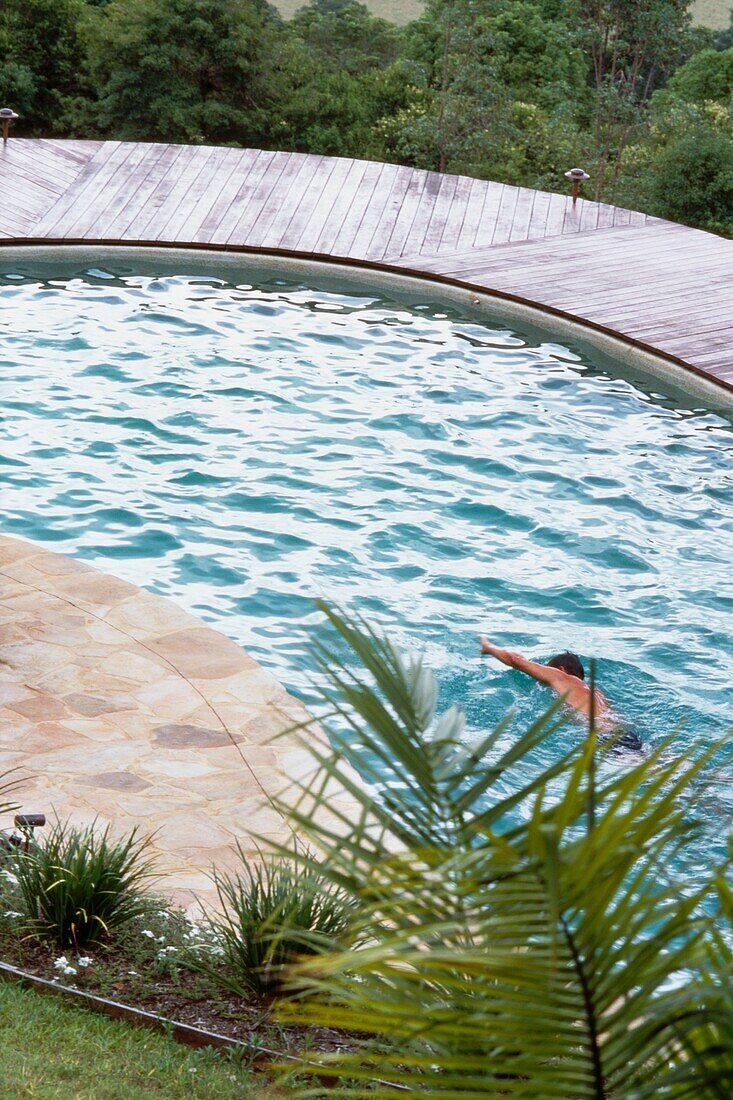 Mann schwimmt in einem Swimmingpool zu Hause