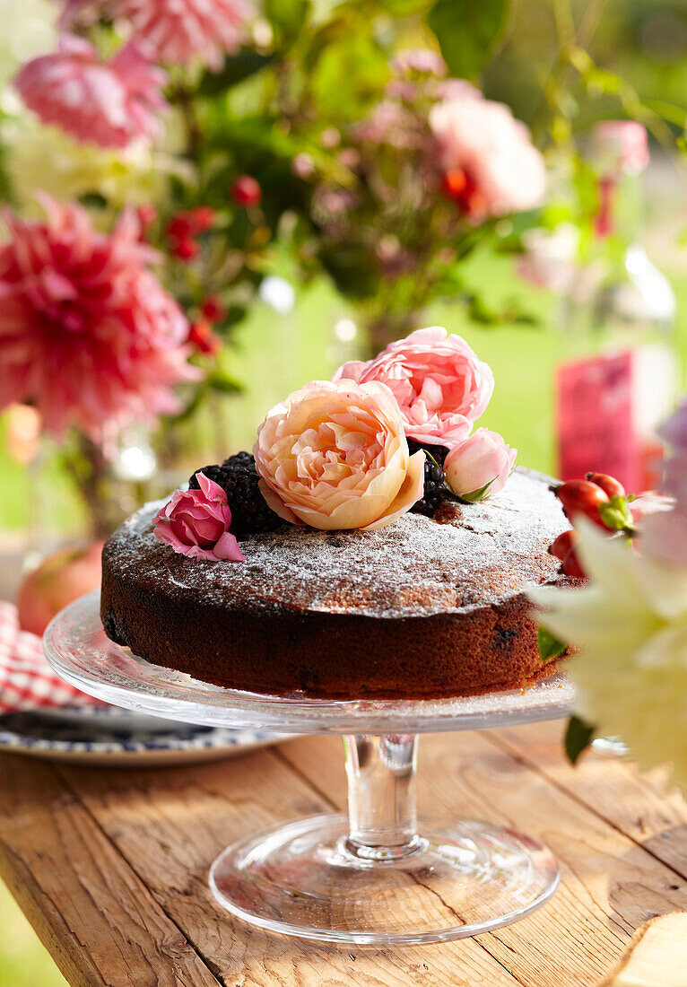 Spätsommerpicknick im Garten mit Kuchen, Obst und Blumen