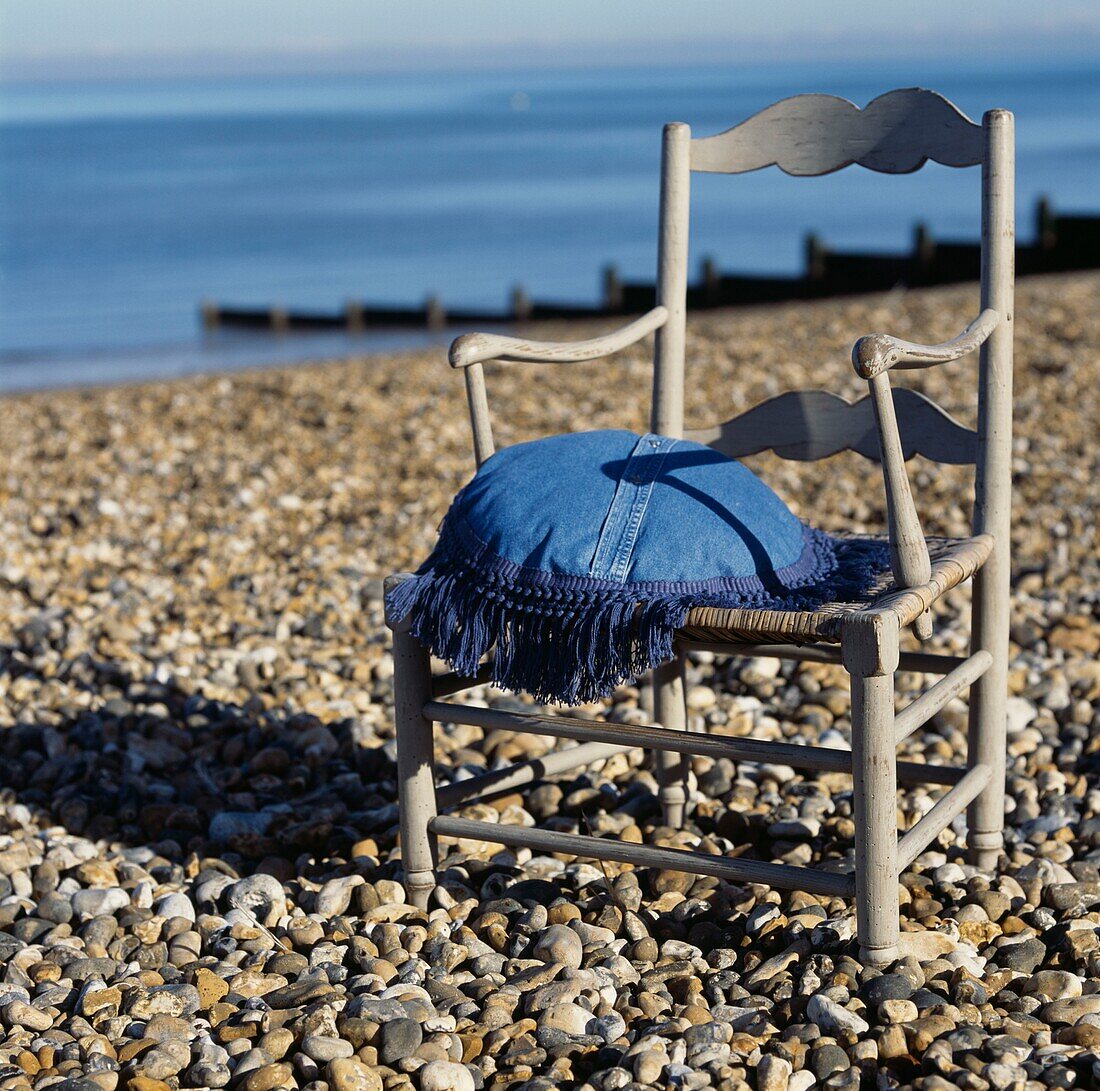 Stuhl im Vintage-Stil mit Kissen an einem Strand