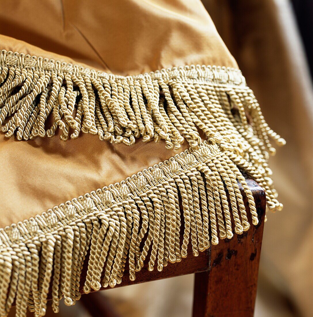 Golden coloured satin throw with fringed trimming