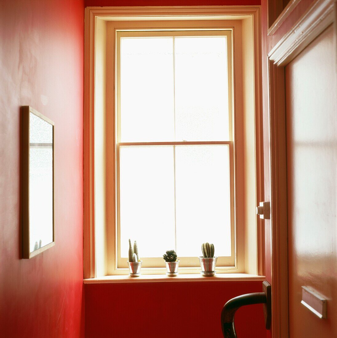 Town house communal entrance hall painted in red with large sash window
