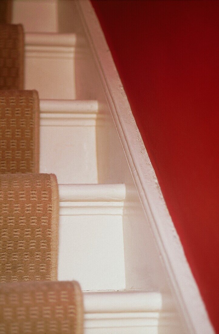 Details einer weiß gestrichenen Treppe mit Teppichläufer