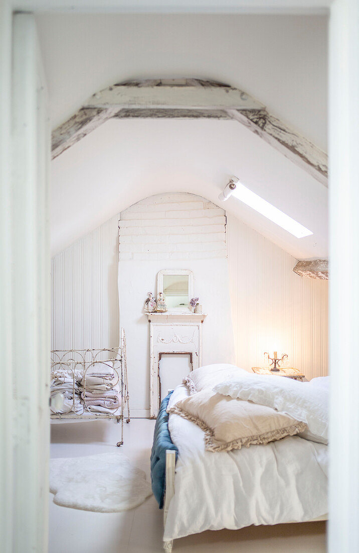 Schlafzimmer im Dachgeschoss mit altem Drahtgitterbett und weißem Dekor
