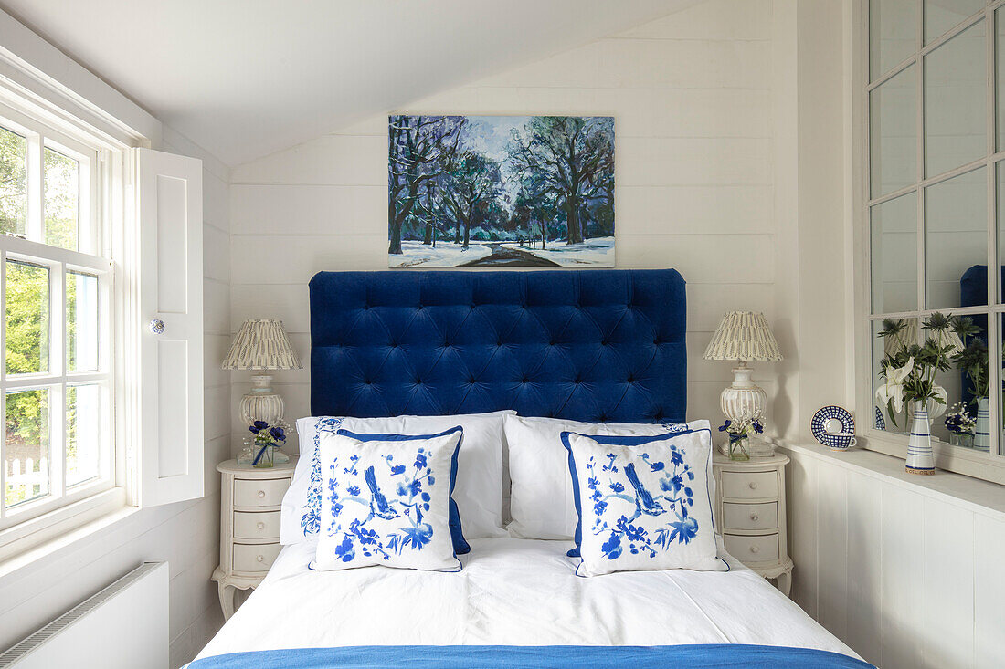 Bedroom with blue velvet headboard and white cushions with blue floral pattern