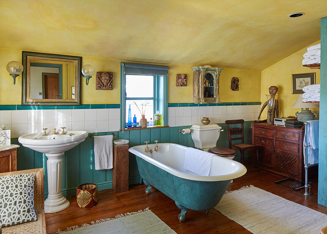Badezimmer mit freistehender Badewanne, Vintage-Möbeln und gelber Wand