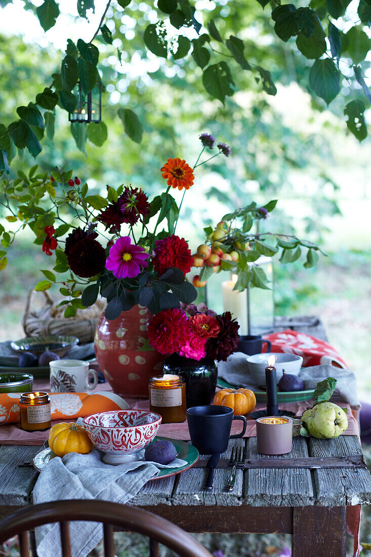 Table set in the garden with autumn decorations, flower arrangement and pumpkins