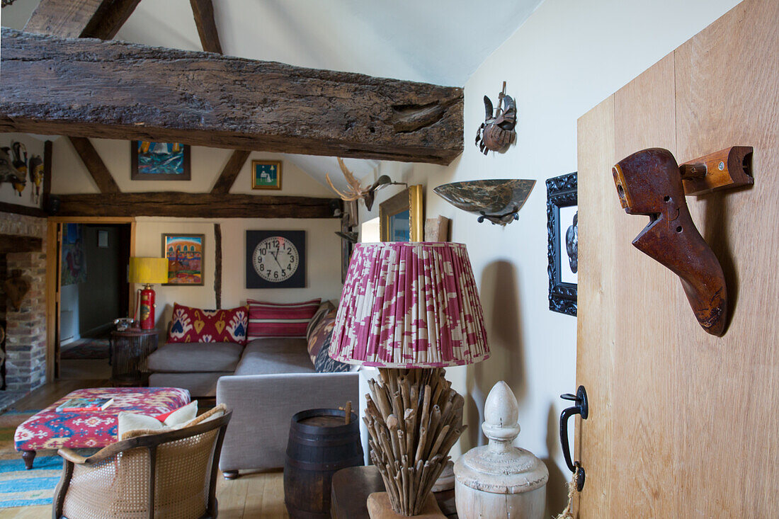 Kunstwerke an der Wand in ländlichem Wohnzimmer mit Holzbalken, antike Schuhform aus Holz als Wanddekoration