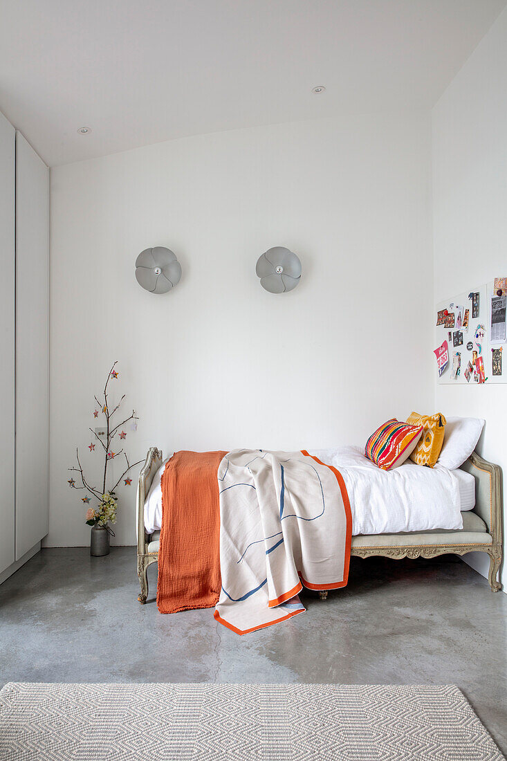 Bett in weißem, minimalistischem Schlafzimmer mit poliertem Betonboden