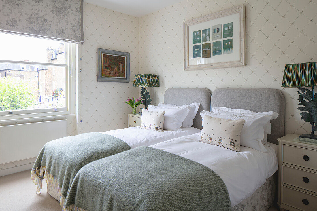 Two single beds in the guest room with light colored wallpaper