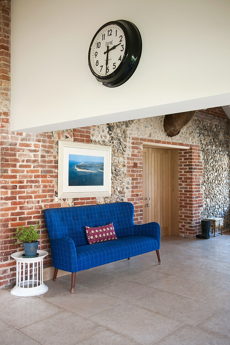 Blue sofa against brick wall in entrance hall