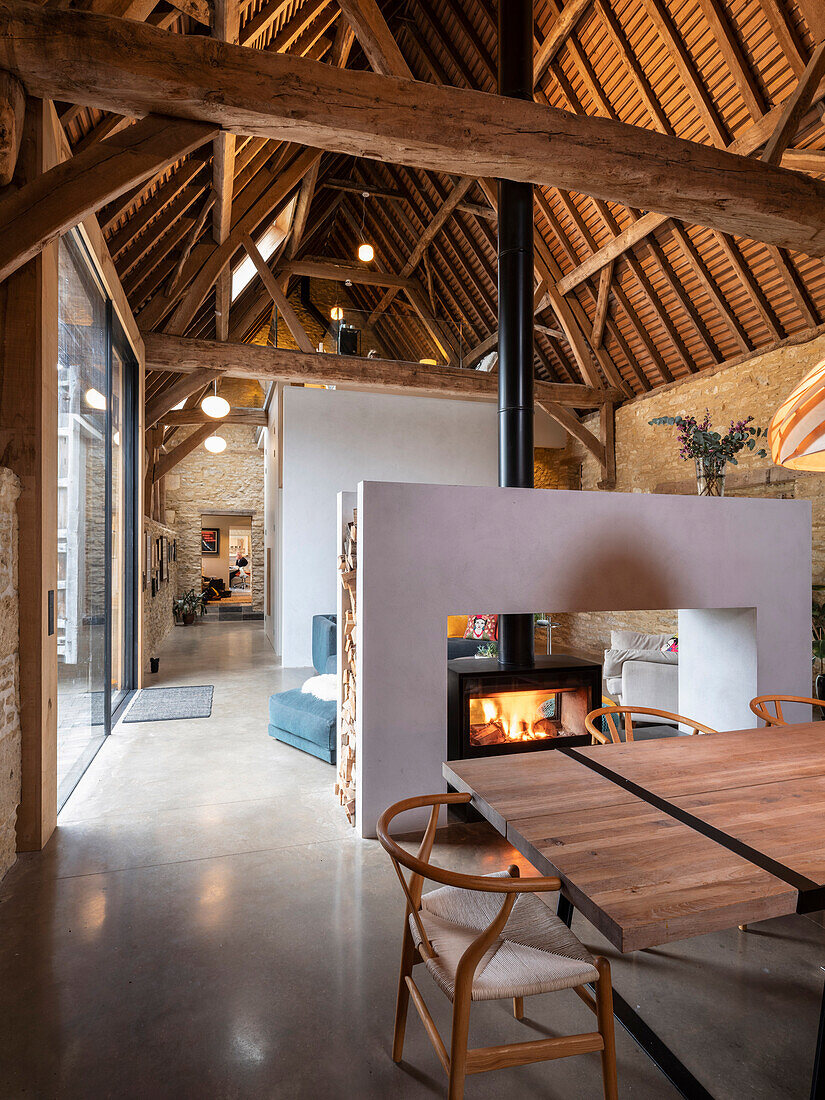 A view of a living room with large double sided fireplace in a former barn