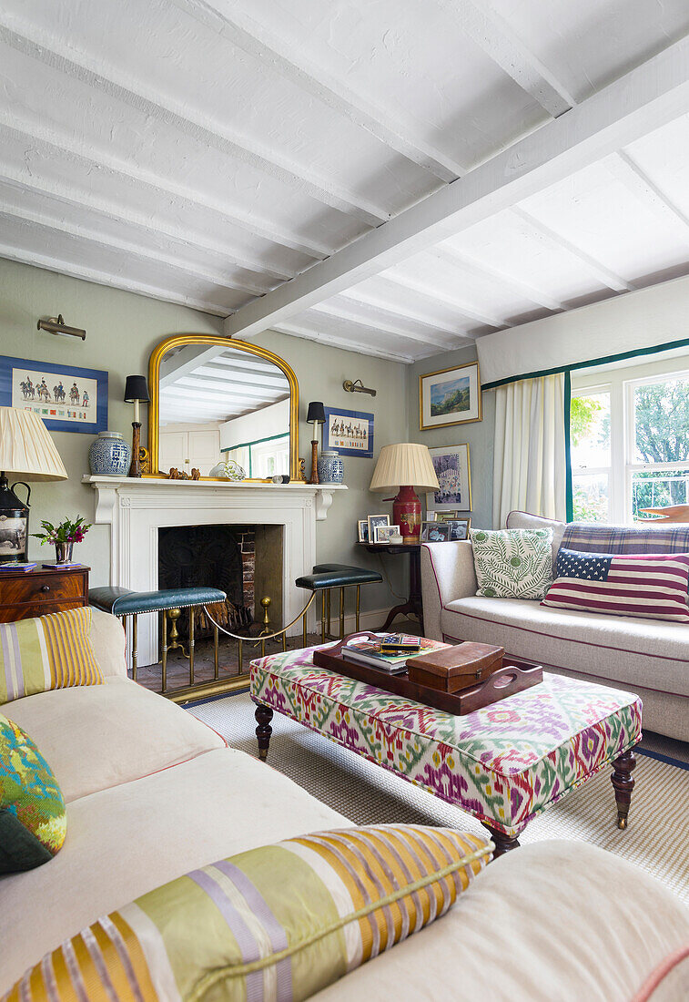 Living room with fireplace, patterned stool and mirror on the mantelpiece