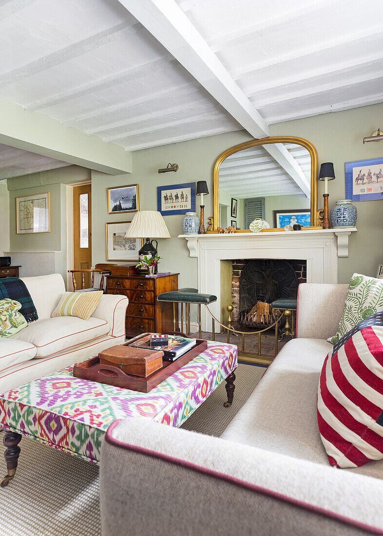 Living room with patterned stool, fireplace and mirror, wooden ceiling and decorative pillows