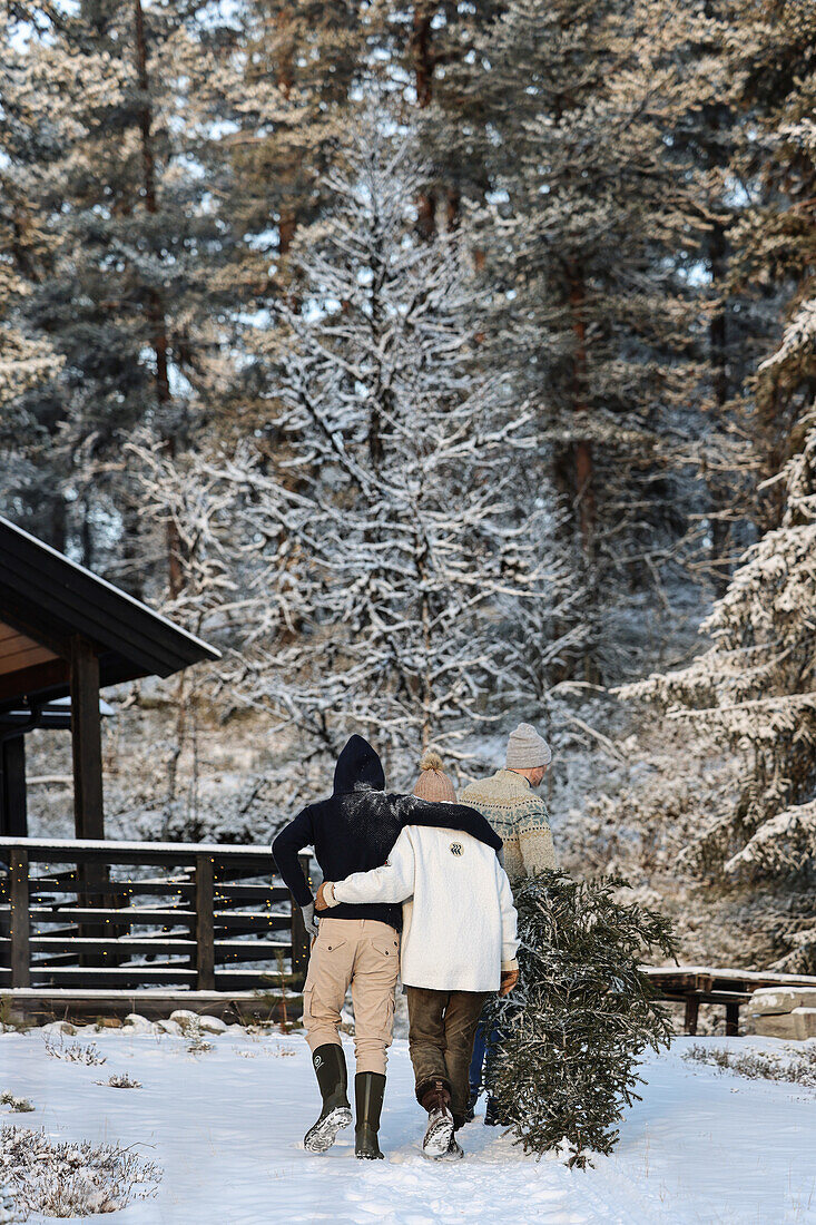 People fetching a Christmas tree in a snowy landscape