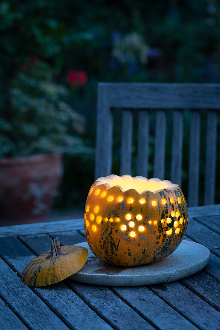 Pumpkin lantern on wooden table in the garden at dusk