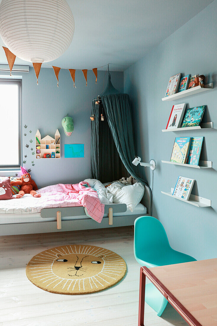 Children's room with wall shelves, bed with canopy and lion rug