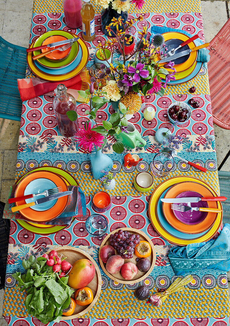 Colorful outdoor table with fruit bowls, radishes and flowers