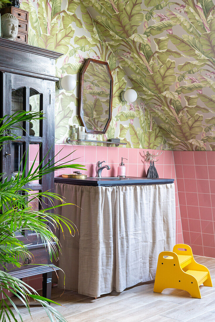 Badezimmer mit tropischem Tapetenmuster und rosa Kacheln