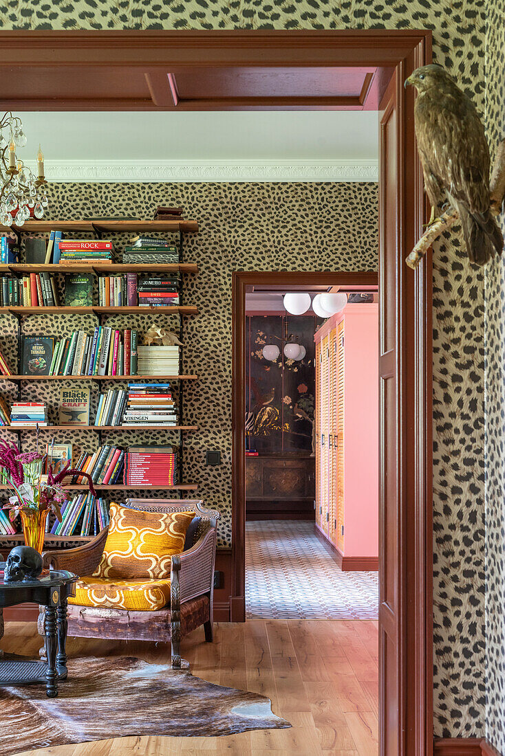 Wohnzimmer mit Leopardenmuster-Tapete, Bücherregal und Rattansessel