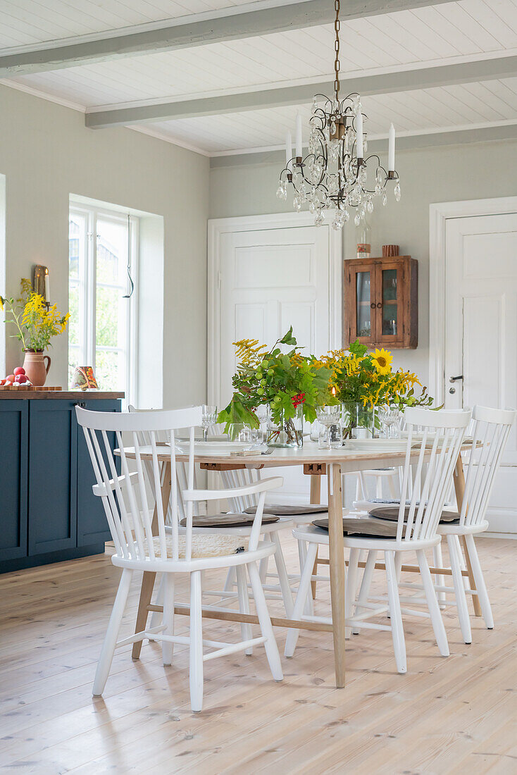 Dining area with white wooden table and chairs and bouquets of flowers