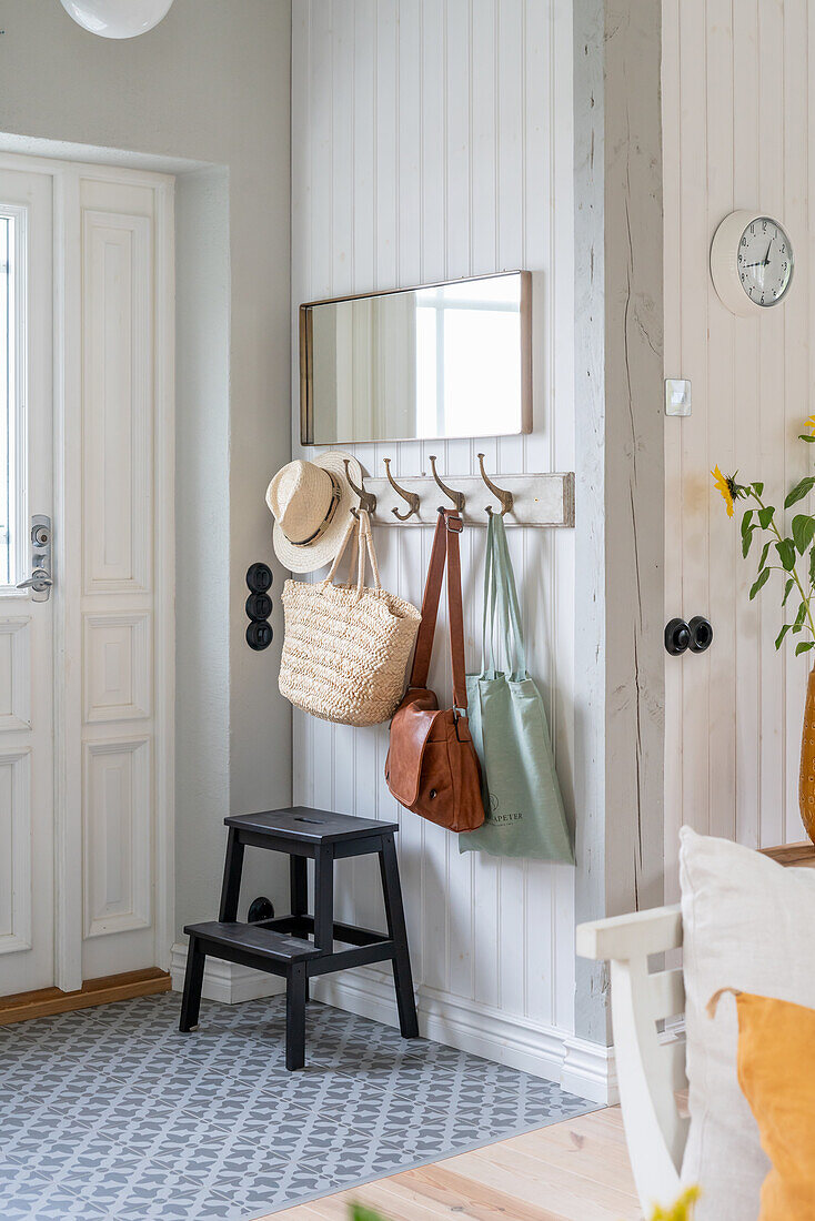 Hallway with wall hooks for bags and black stool