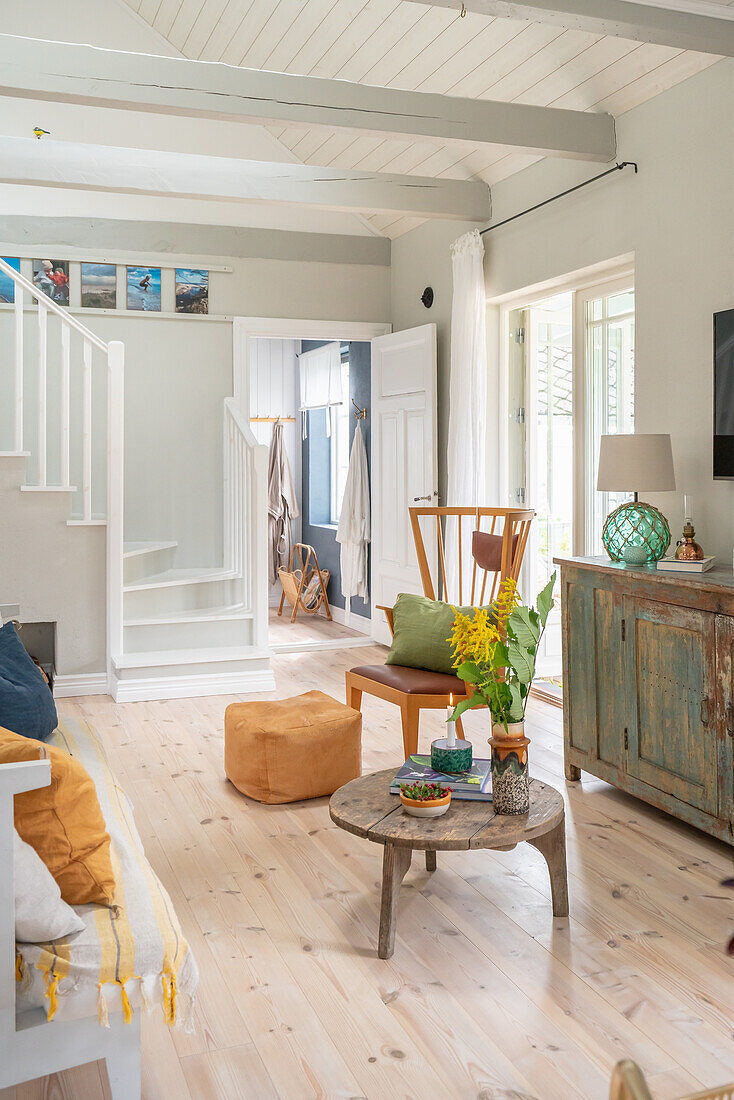 Brightly decorated living room with wooden furniture and bouquet of flowers on side table