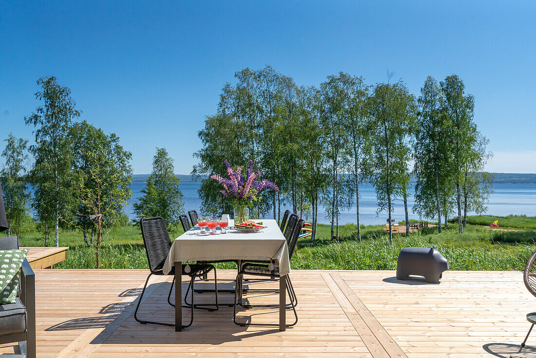 Terrace with lake view, set table and wooden floorboards