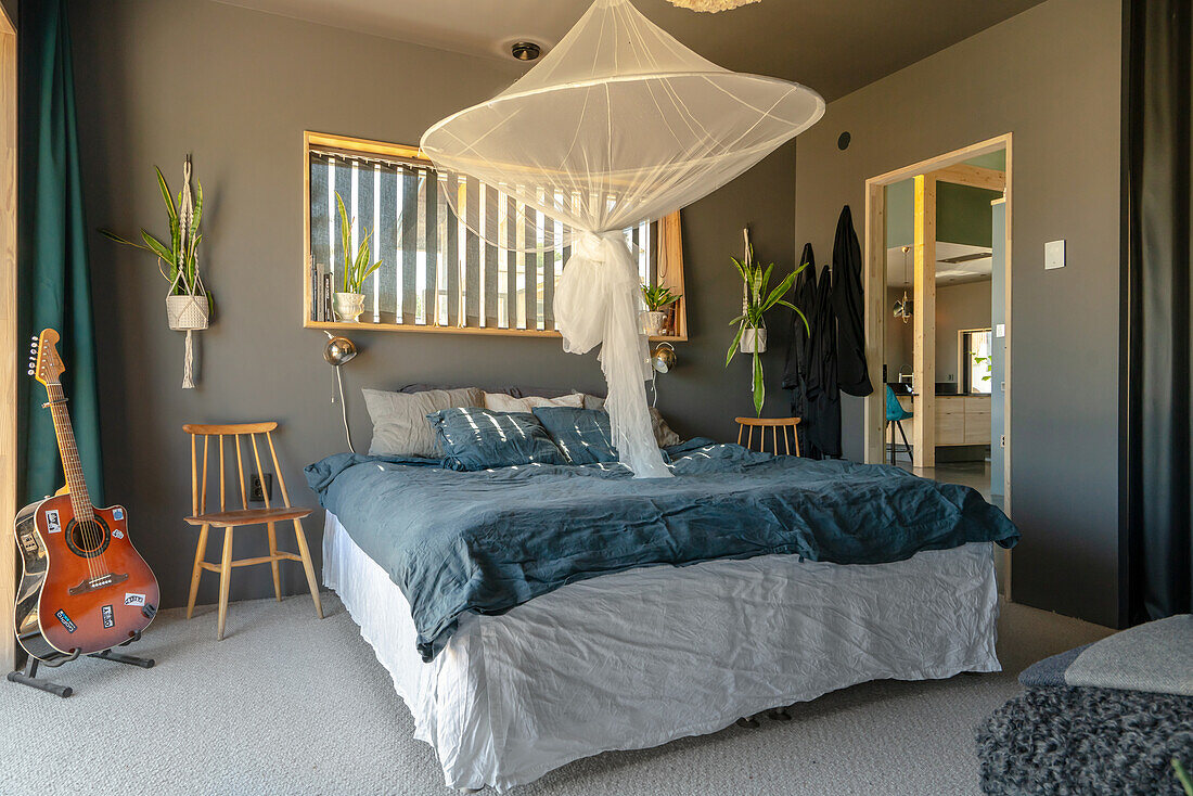 Bedroom with mosquito net, grey walls and guitar