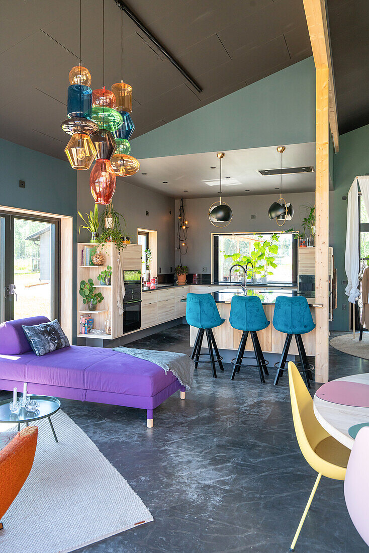 Modern kitchen with bar stools and colourful pendant light, adjoining living room