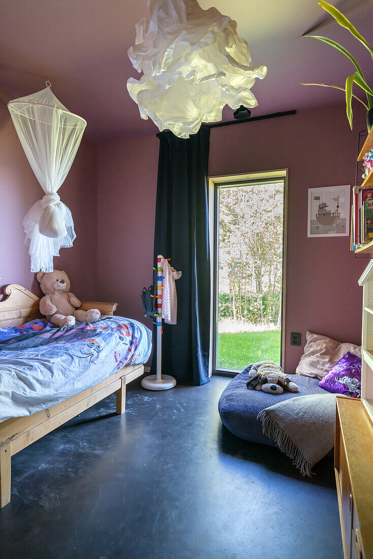 Kinderzimmer mit Bett, rosa Wänden, dunklem Boden und Zugang zum Garten