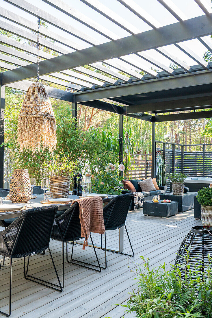 Terrasse mit modernen Möbeln und geflochtener Lampe unter Pergola