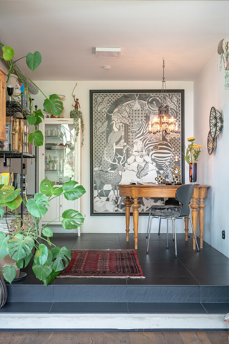 Wooden table with grey chair and large work of art on the wall